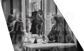 A woman is standing in front of a table with a laptop on it. Description generated by AI